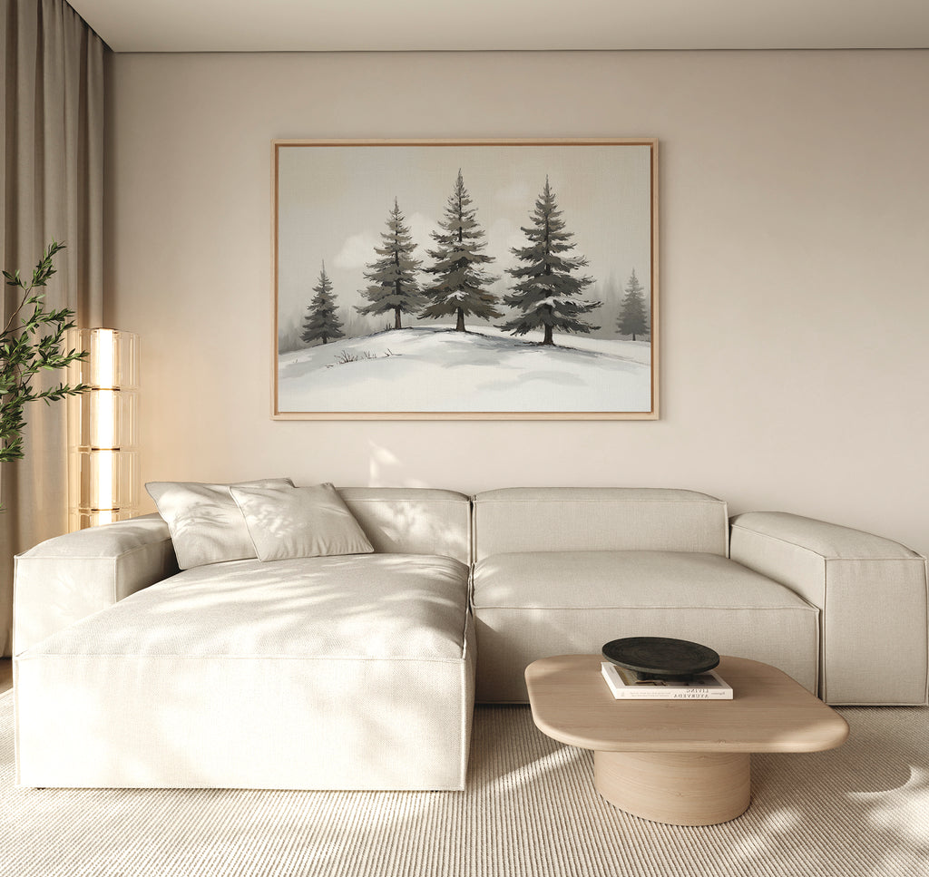 A minimalist living room with a beige sectional, light wood coffee table, and potted plant features the Winter Solitude Canvas Art - Horizontal. Natural light fills the space, evoking calm reminiscent of tranquil bedroom decor.