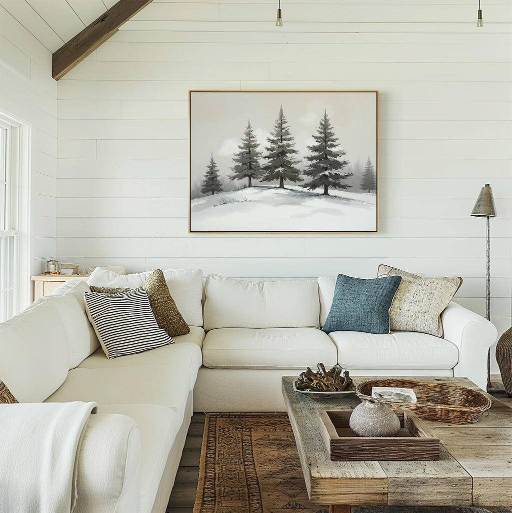 A cozy living room with a white sectional sofa, assorted pillows, a rustic wooden coffee table, and the Winter Solitude Canvas Art - Horizontal depicting snow-covered pine trees above the sofa. Decor includes neutral tones and natural textures.
